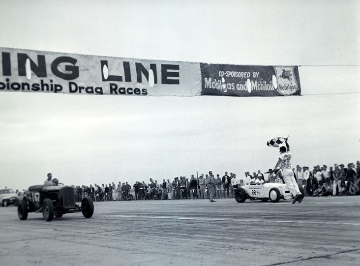 A flag starter gives the go signal at the first Nationals in 1955.